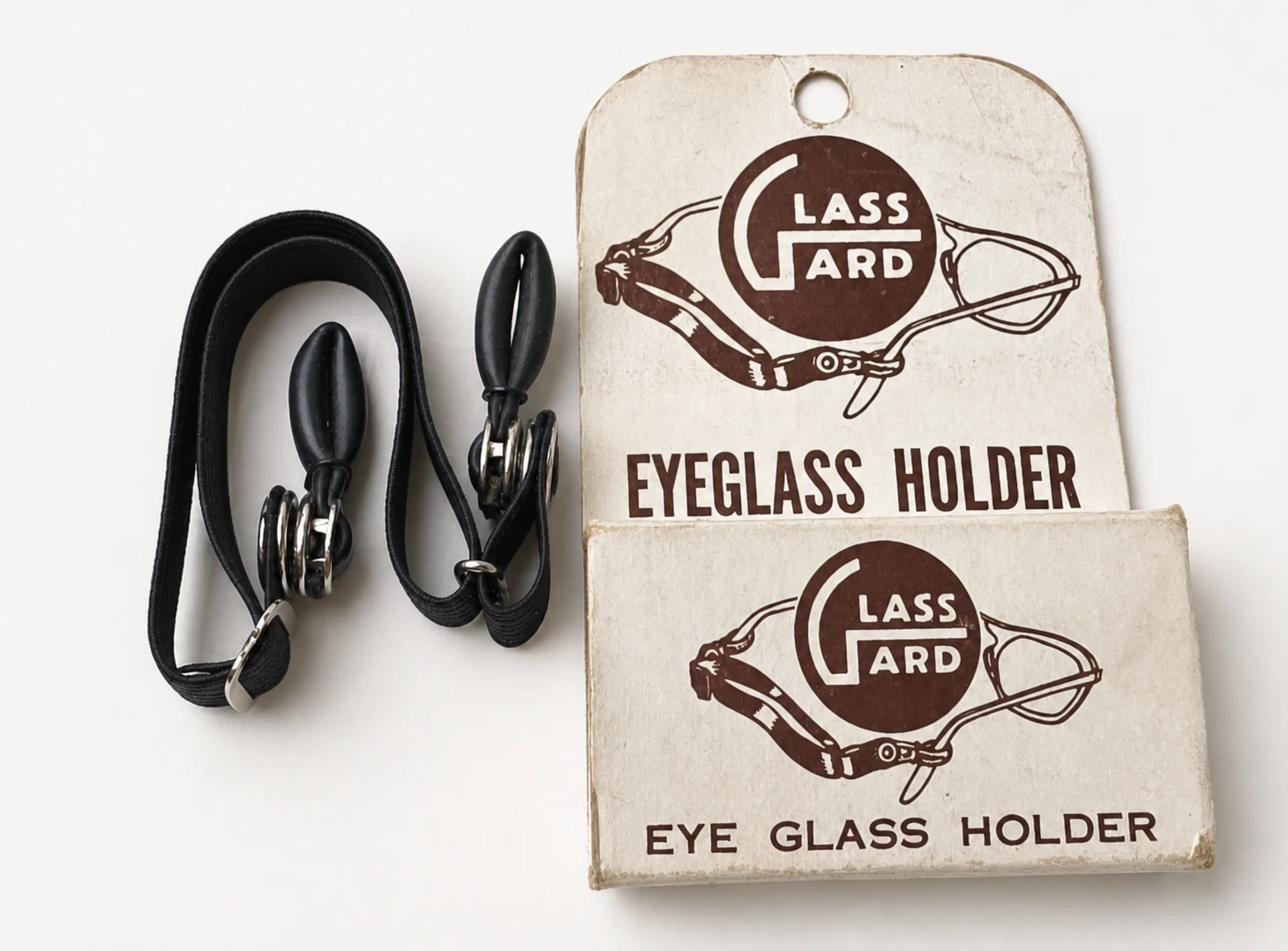 Restored archival photograph of an original Glass-Gard eyeglass holder beside its illustrated box